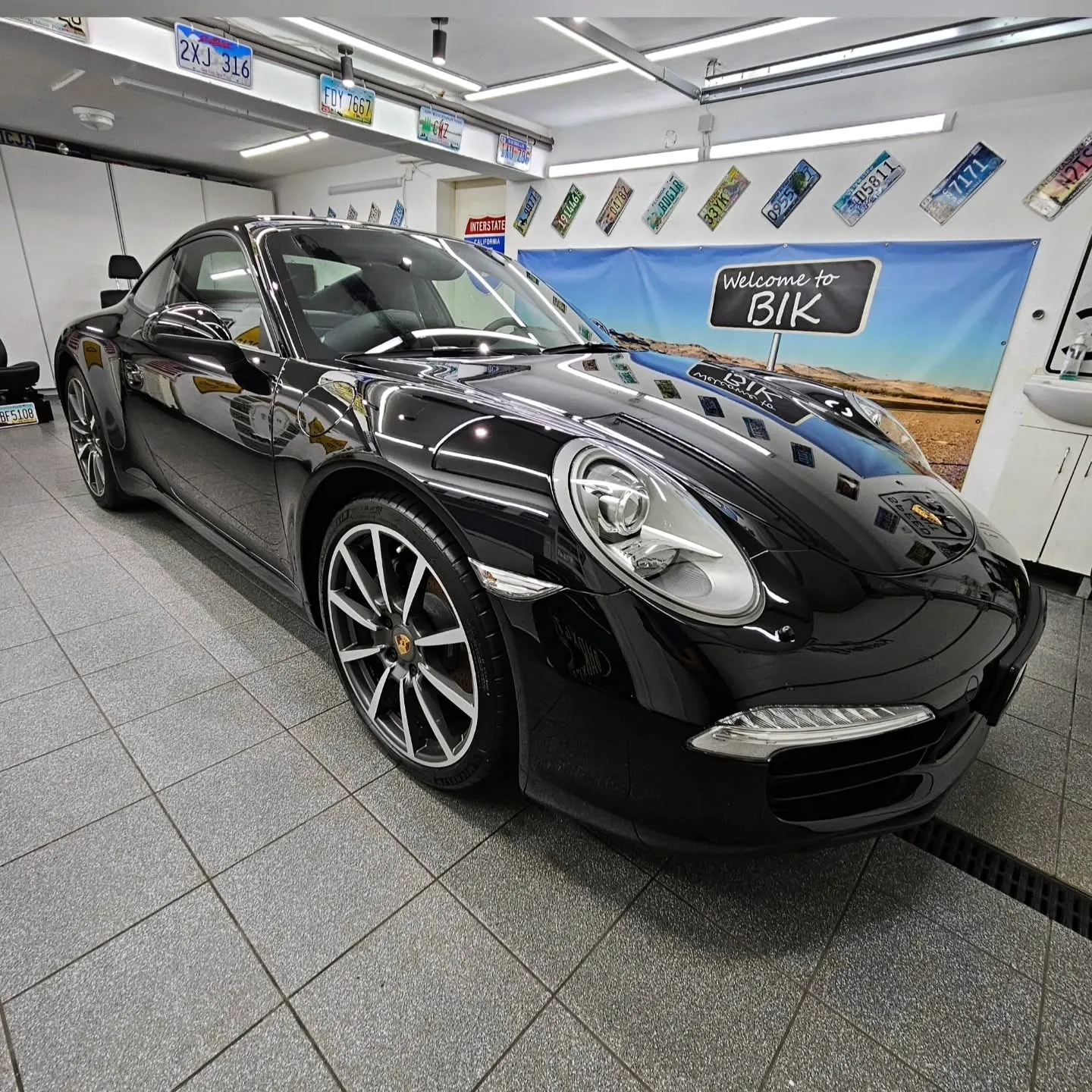 Czarne Porsche 911 ustawione bokiem w studiu BIK, obok tablica z napisem Welcome to BIK